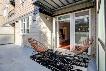 a patio with two chairs and a rug in front of a house  at 128 on State, Kirkland, 98033